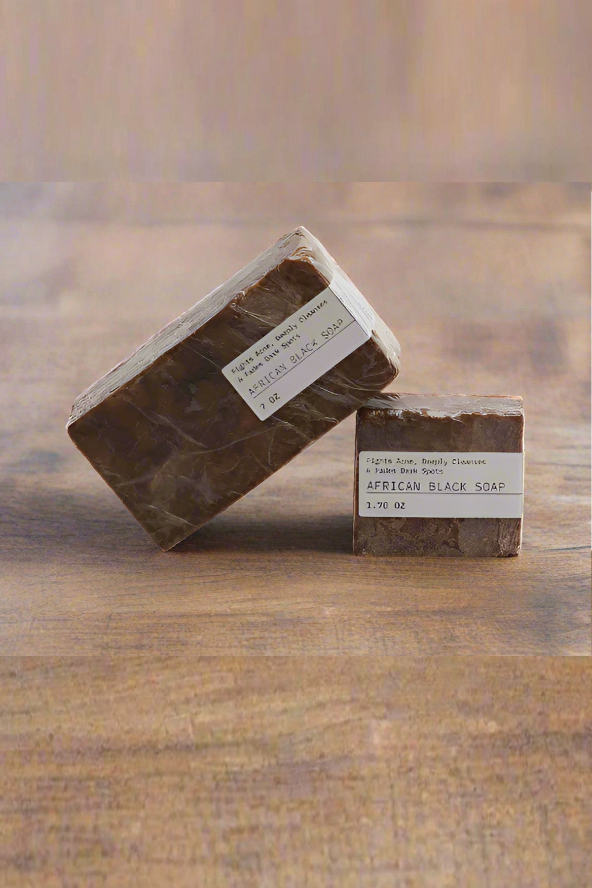 Two bars of African Black Soap on a wooden surface with a blurred background