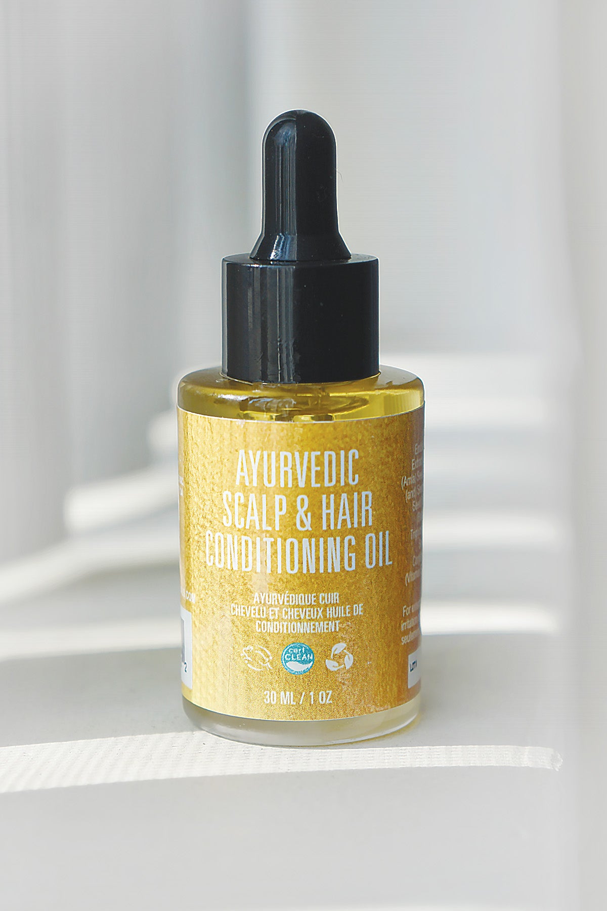 Ayurvedic scalp and hair conditioning oil bottle with dropper on a white background