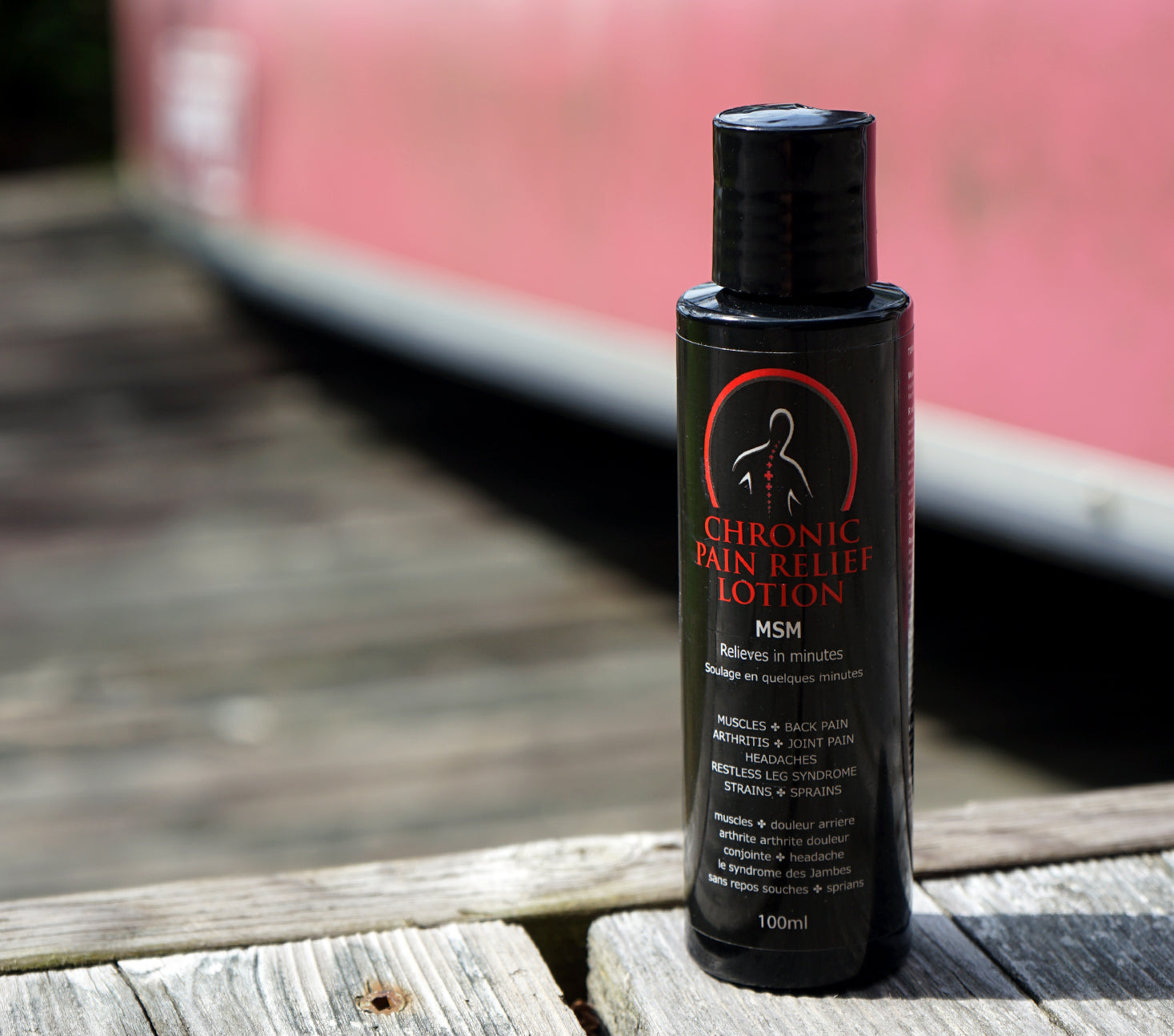 Bottle of Chronic Pain Relief Lotion on a wooden surface with a blurred background