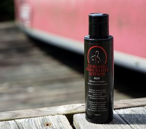 Bottle of Chronic Pain Relief Lotion on a wooden surface with a blurred background