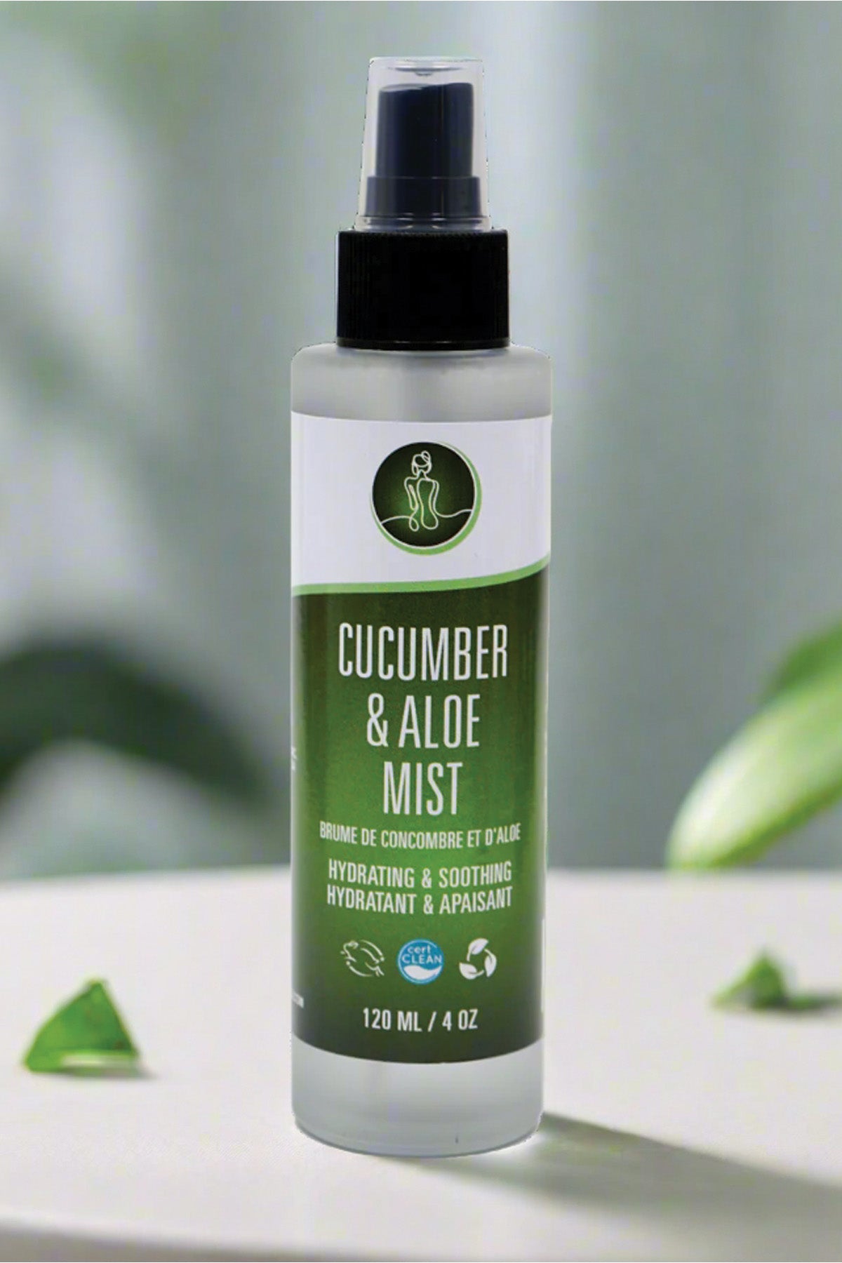 Bottle of cucumber and aloe mist on a white surface with green leaves in the background