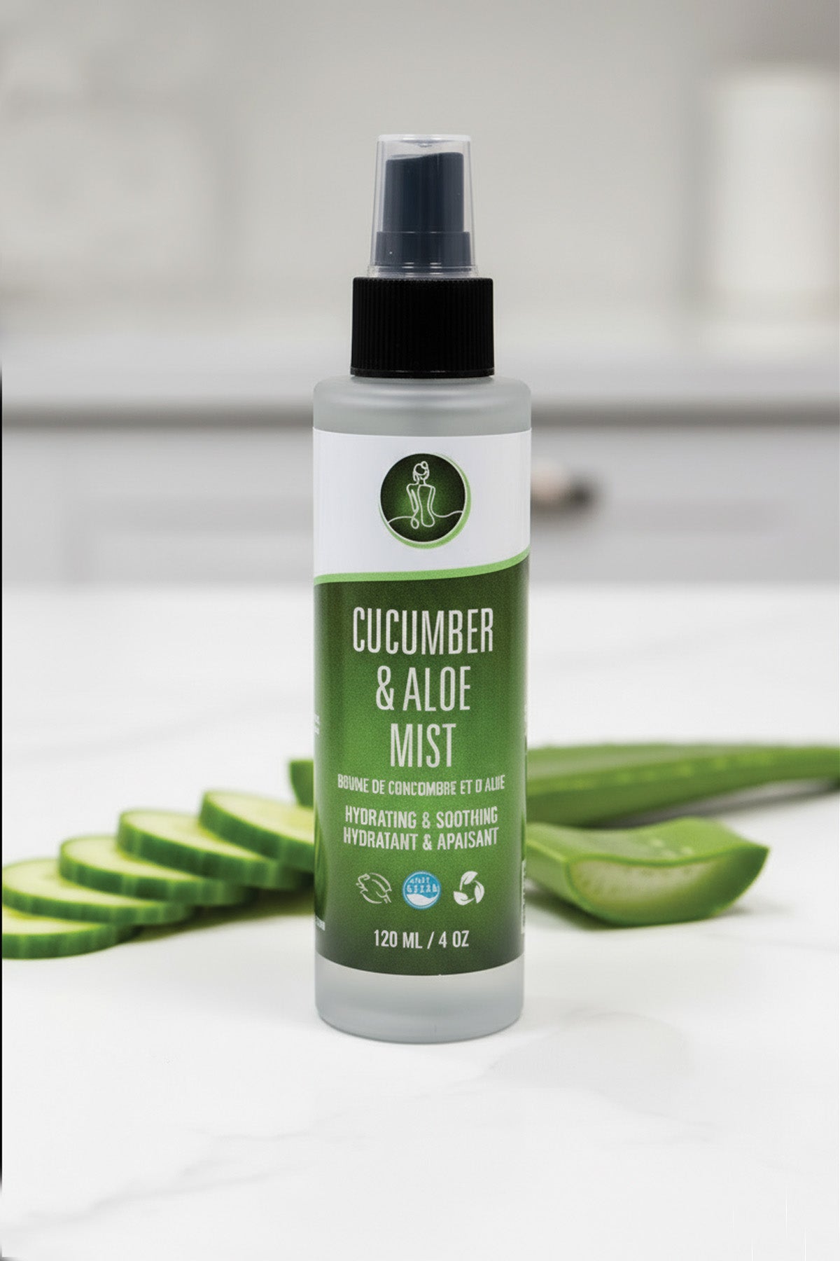 Bottle of cucumber and aloe mist with sliced cucumbers and aloe vera leaves on a white background