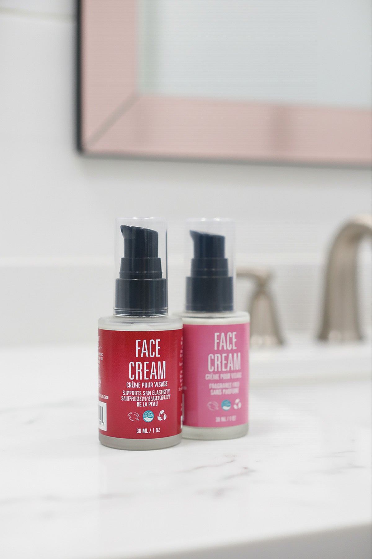 Two bottles of face cream on a bathroom counter with a mirror in the background.