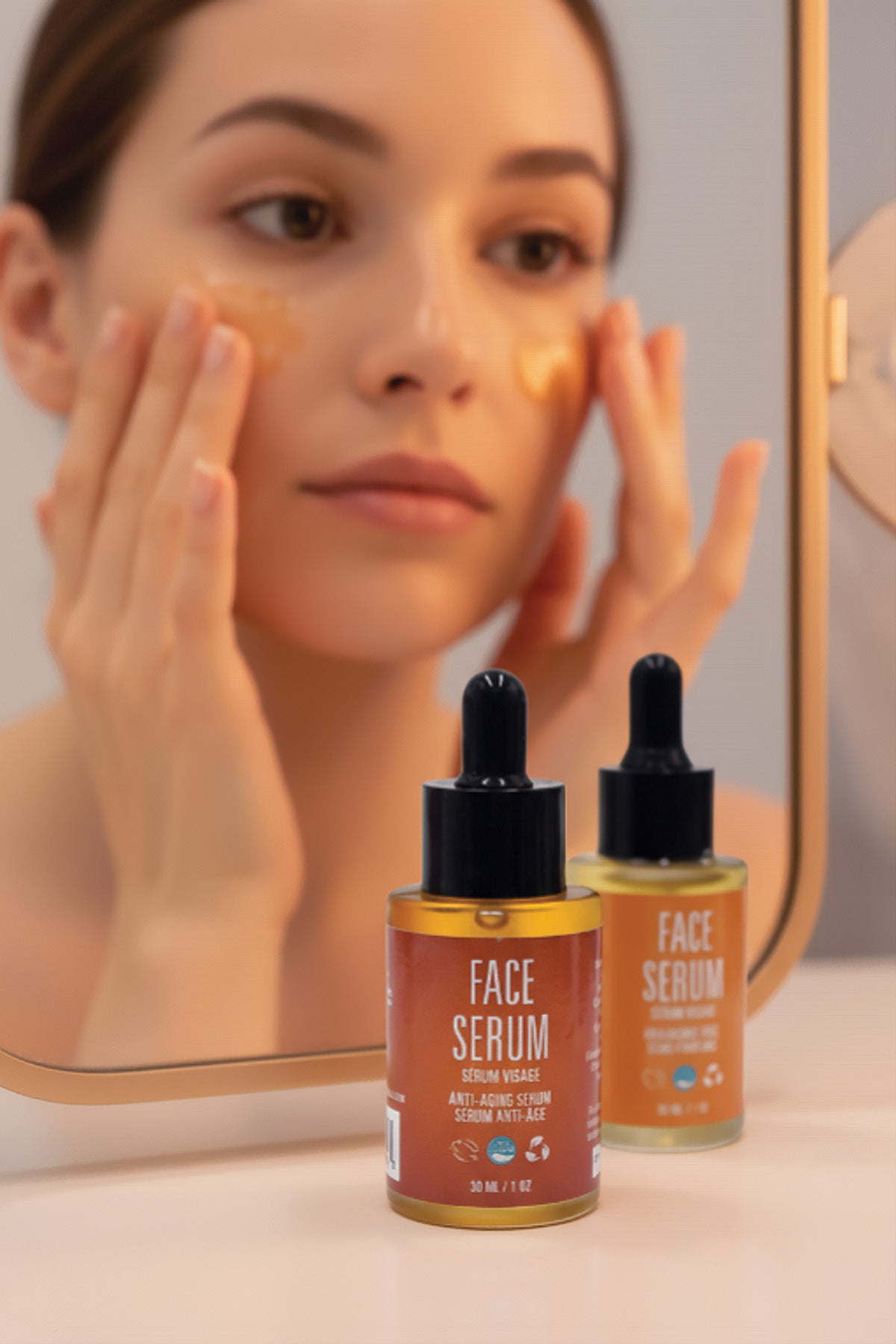 Two bottles of face serum with a woman applying serum to her face in the background.