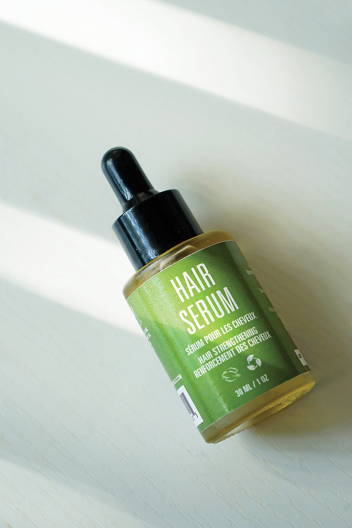 Hair serum bottle with dropper on a light background