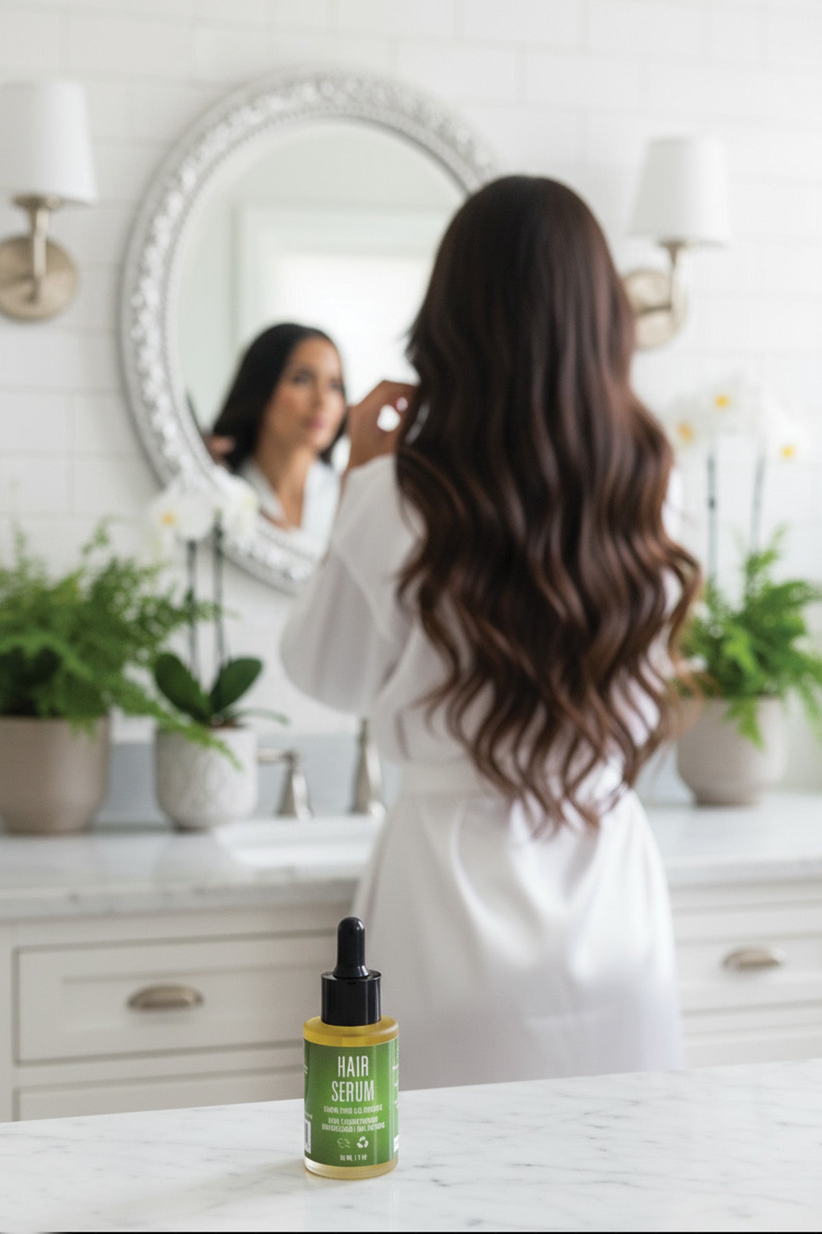 Woman with long hair looking at herself in the mirror, with a bottle of hair serum on a counter.