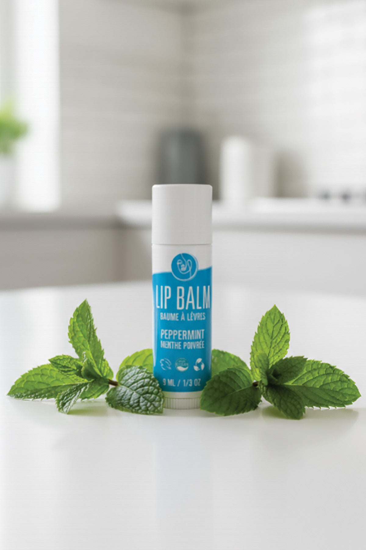Lip balm with peppermint leaves on a white surface