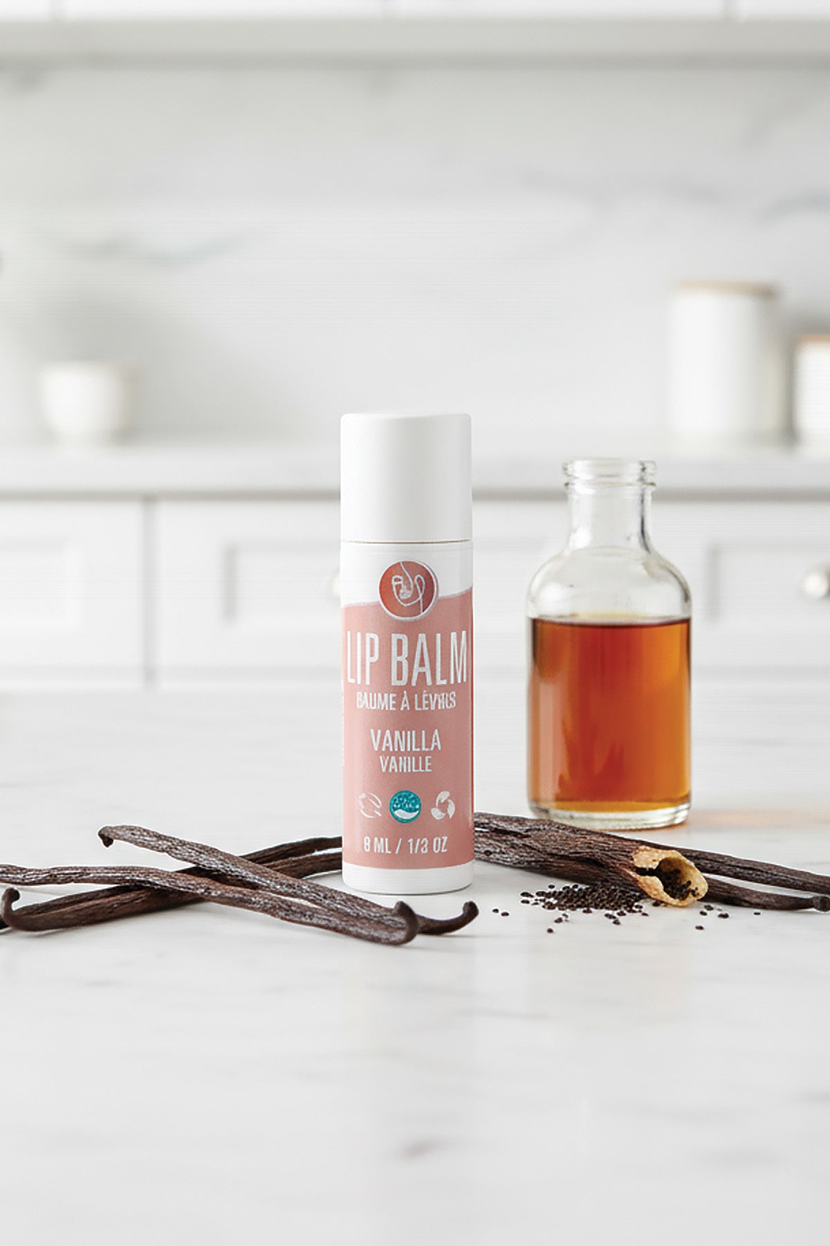 Lip balm with vanilla flavor on a white surface with vanilla beans.