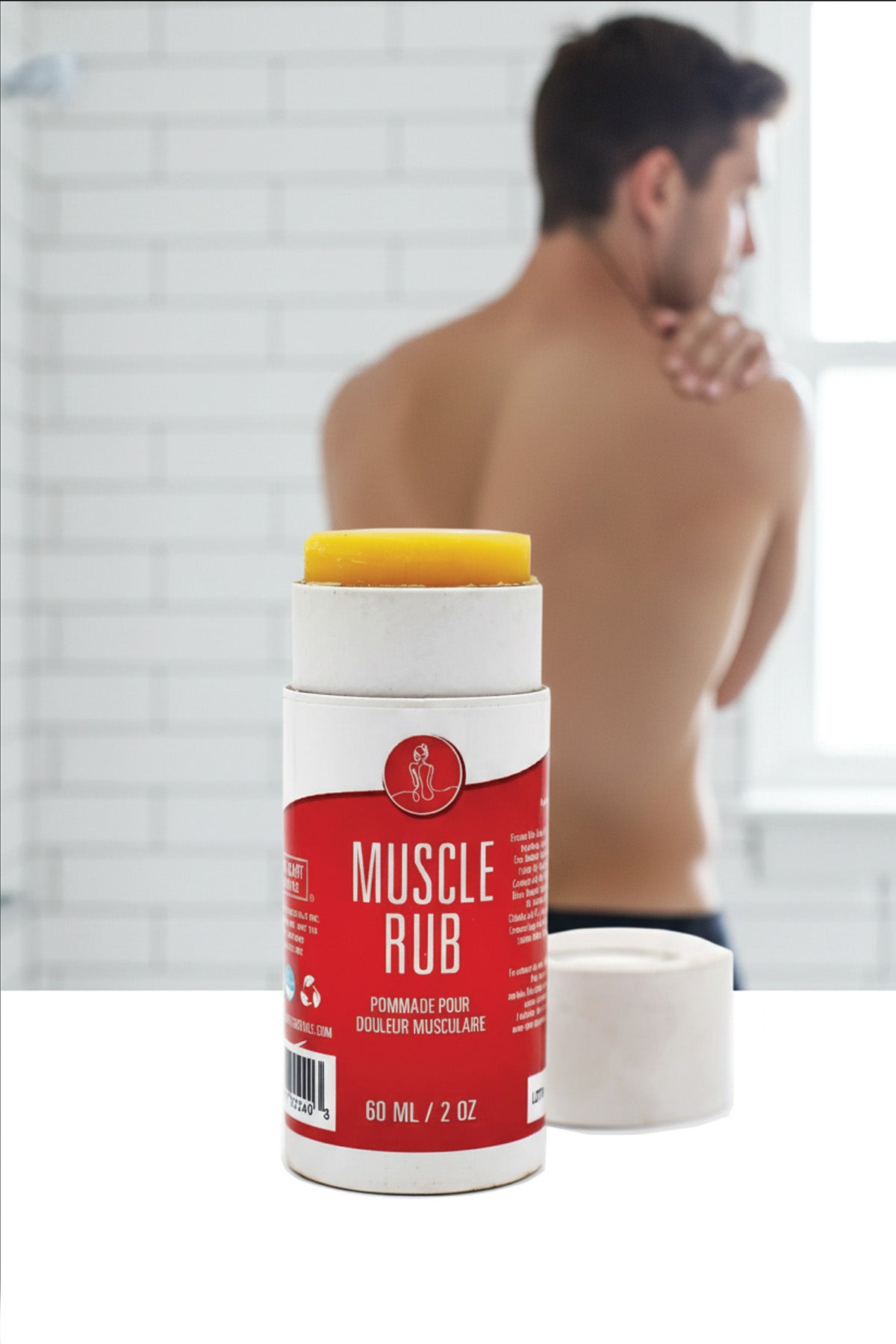 Red bottle of muscle rub with a yellow cap on a white surface, blurred background
