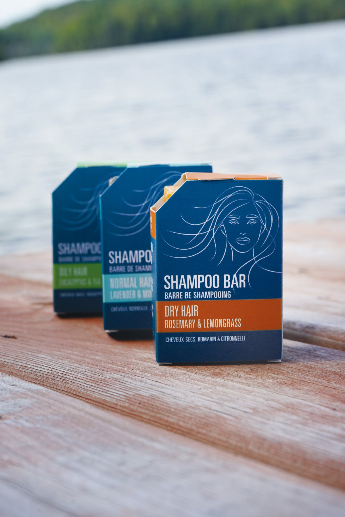 Three shampoo bars on a wooden surface with a blurred natural background