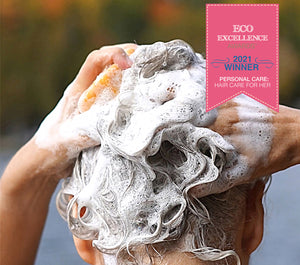 Person washing hair with shampoo bar, with a '2021 Eco Excellence Winner' badge on a pink background.