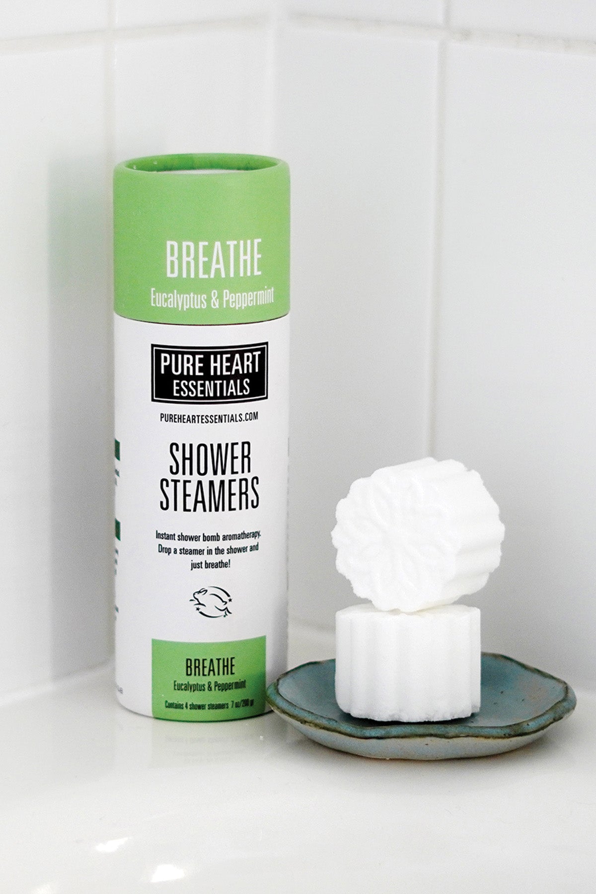 Shower steamers with packaging labeled 'Pure Heart Essentials' on a white tiled background