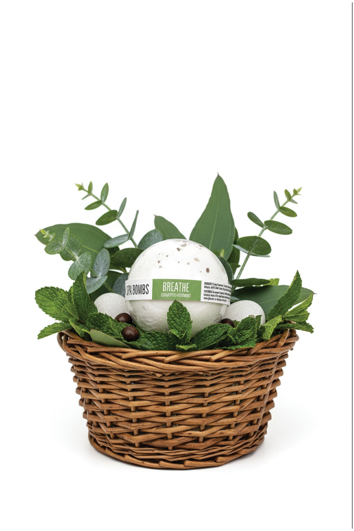 Basket with bath bombs and greenery on a white background
