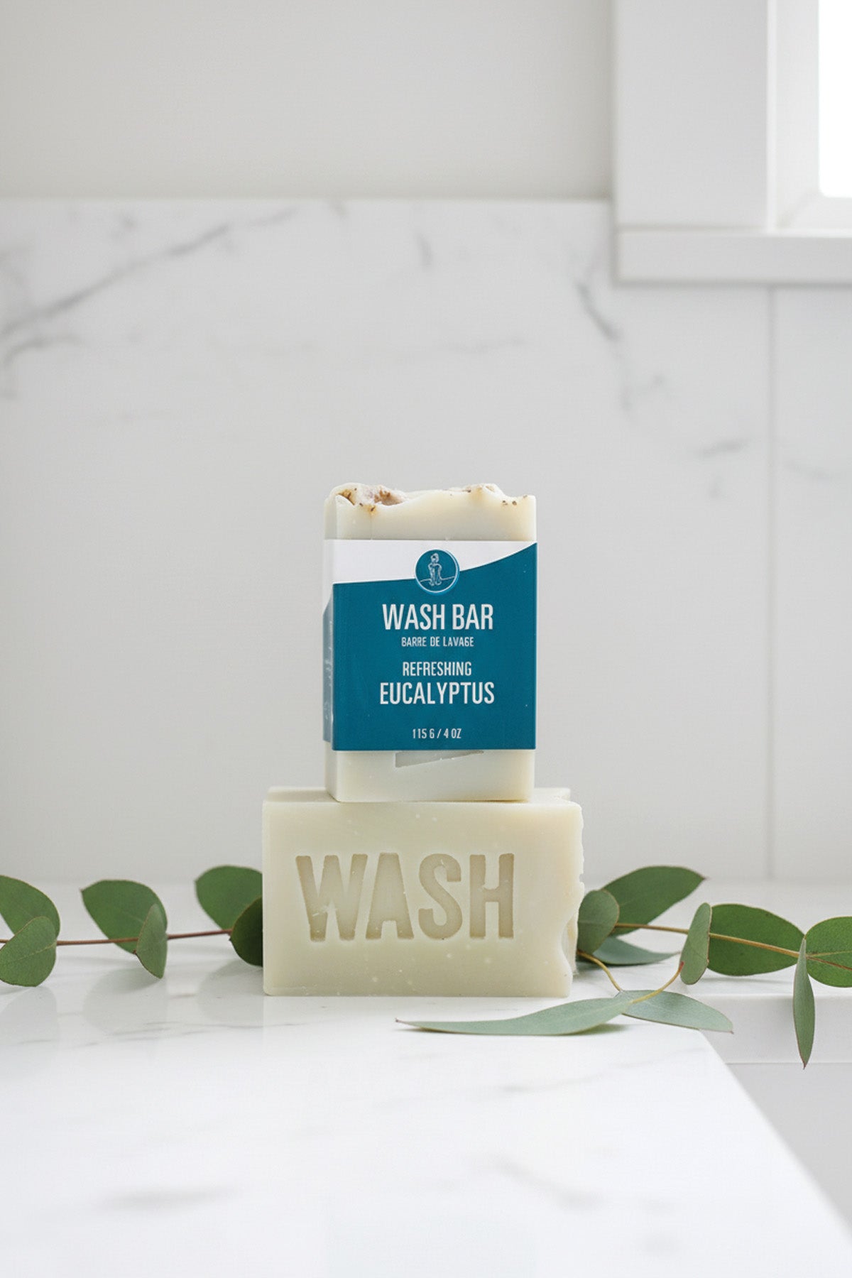 Bar of soap with a blue label on a white surface with green leaves