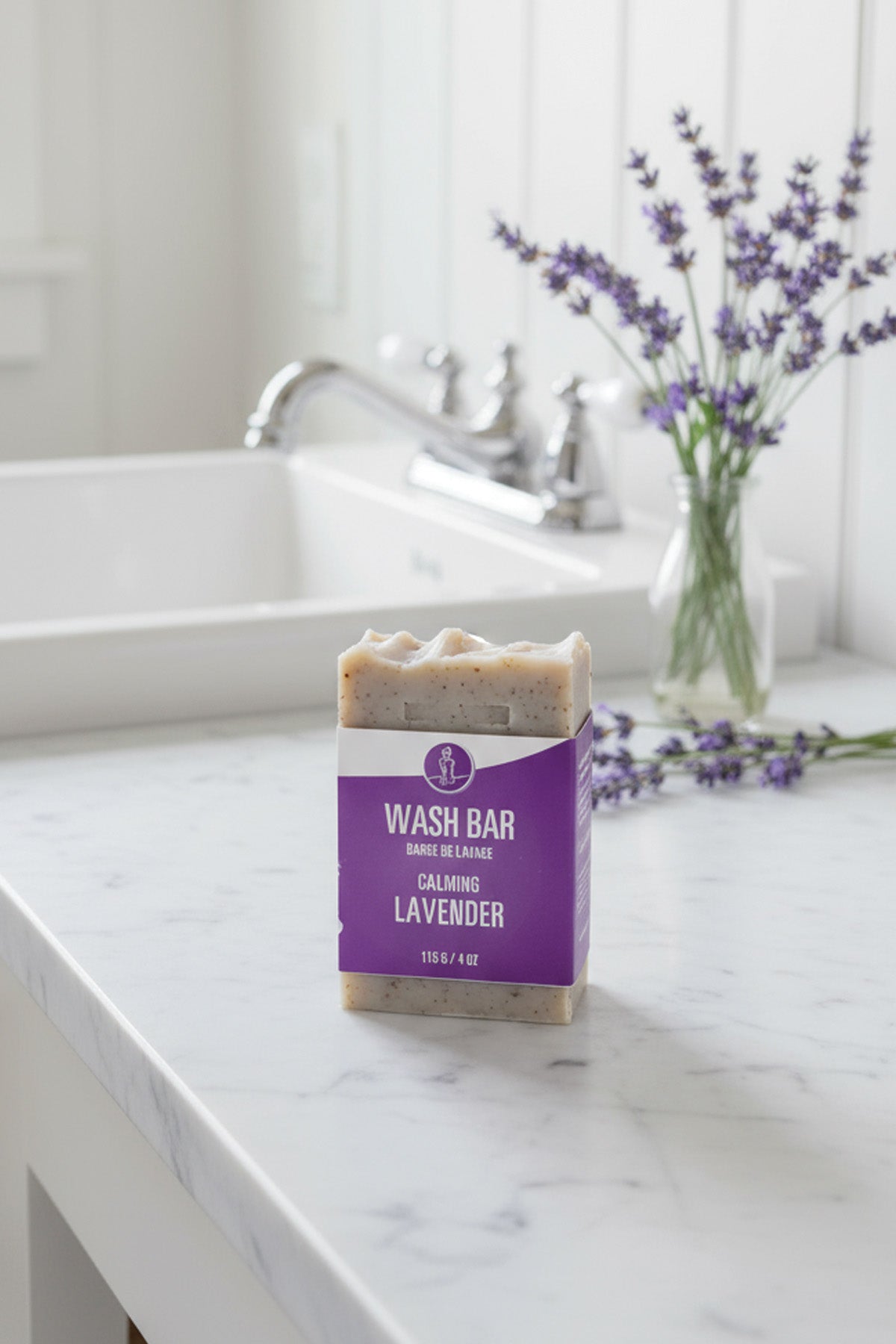 Bar of soap with a purple label on a marble countertop with lavender flowers.