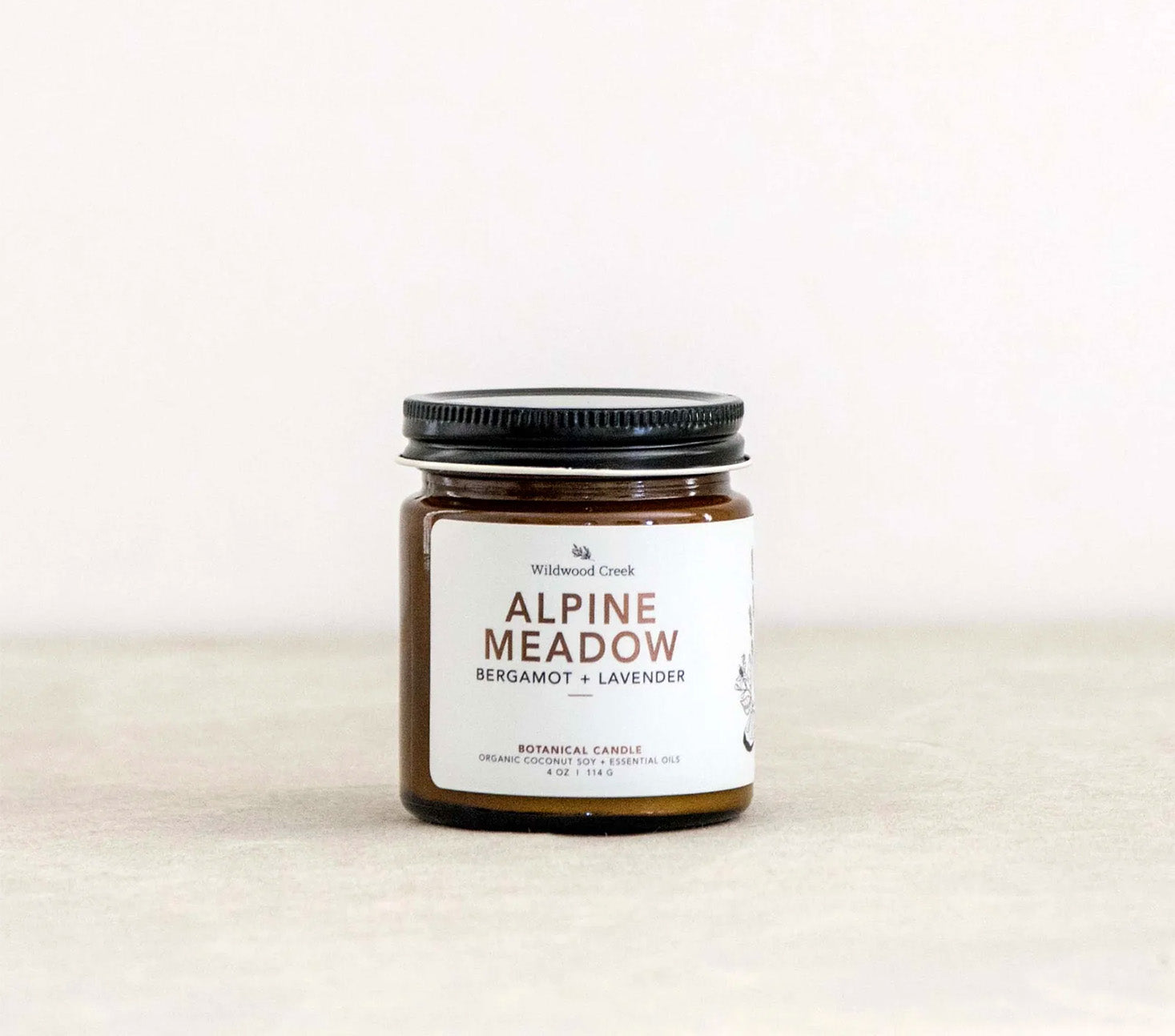 Jar of 'Alpine Meadow' candle with a label on a white background
