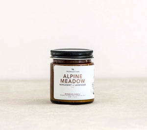 Jar of 'Alpine Meadow' candle with a label on a white background